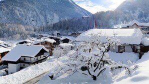 A snow-covered village with traditional wooden houses, a church, and mountains in the background. - Cosy apartment for 4 people with WIFI, TV and balcony (Grossdornau)