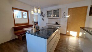 A modern kitchen with a central island, wooden flooring, and pendant lighting. - Cosy apartment for 8 people with WIFI, TV and balcony (Grossdornau)