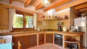 A compact kitchen with wooden beams, a built-in oven, a sink, and a refrigerator. - Wonderful private villa for 6 guests with WIFI, private pool, TV, patio and panoramic view (Inca)