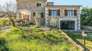 A stone house with a central archway, a garage, and a well-maintained garden.