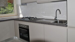 A modern kitchen with white cabinets, a gas stove, a built-in oven, and a stainless steel sink. - Nice apartment for 6 guests with A/C, TV, balcony and pets allowed (Formia)
