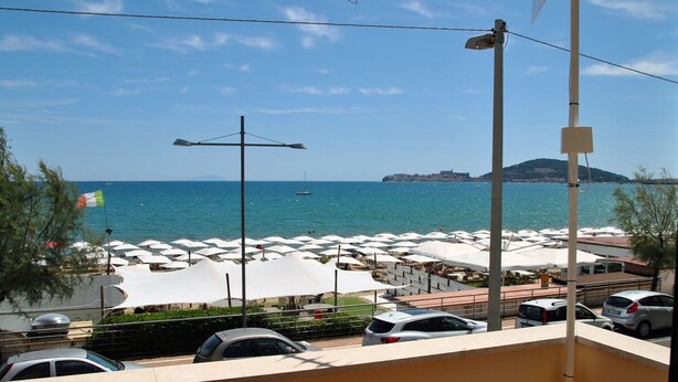 A coastal view with a beachside restaurant, white umbrellas, and a parking area. - Nice apartment for 6 guests with A/C, TV, balcony and pets allowed (Formia)