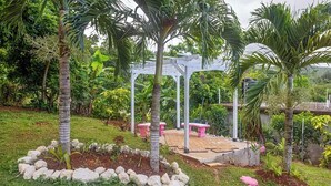Un jardin agrémenté d’un kiosque, de palmiers et d’un espace aménagé pour s’asseoir.