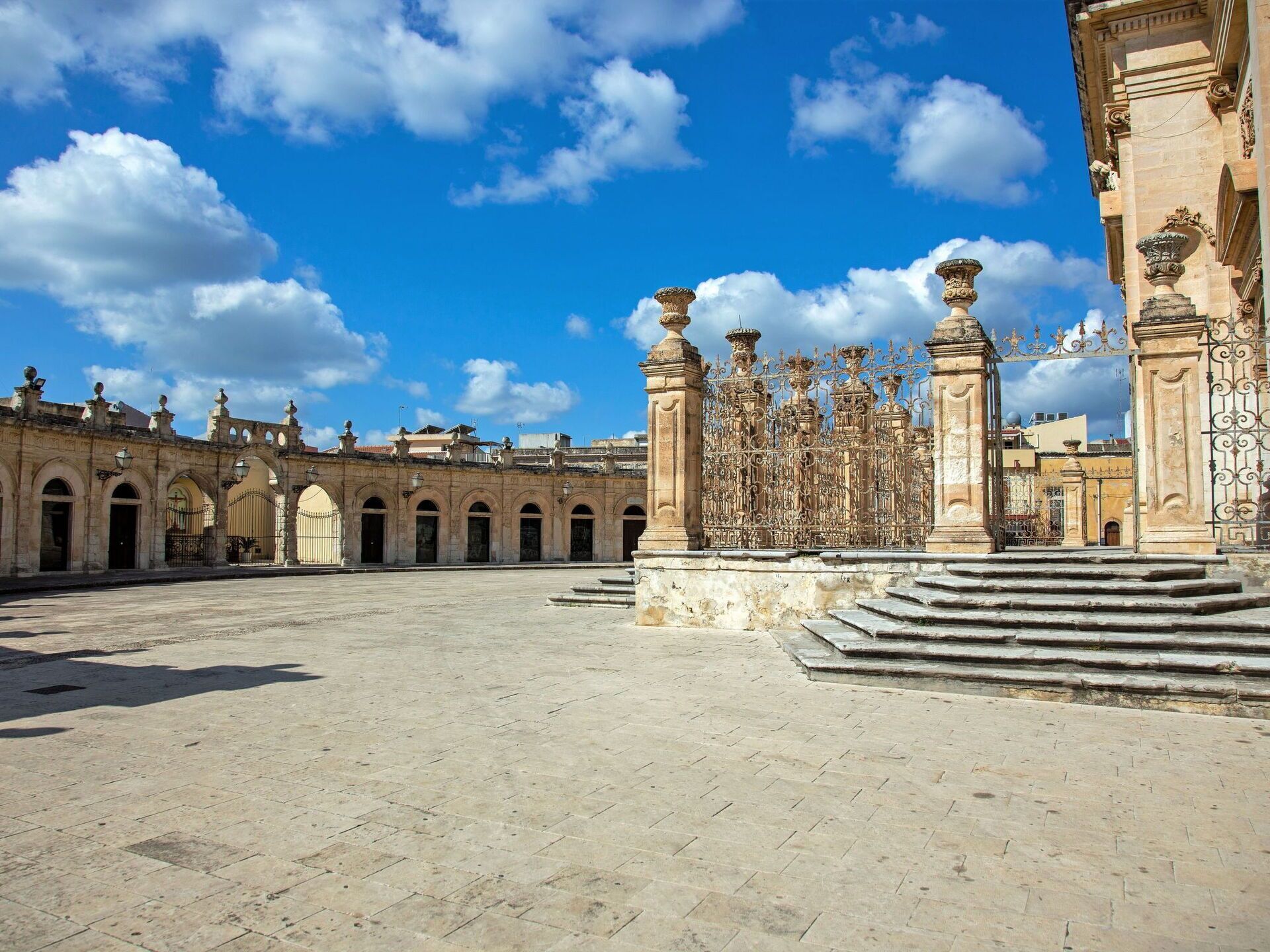 A spacious courtyard with a fountain, ornate columns, and a clear blue sky.