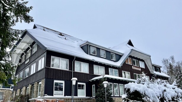 A large, dark-colored building with multiple windows and a snow-covered roof.