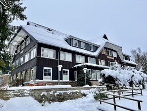 A large, dark-colored building with multiple windows and a snow-covered roof. - Nice apartment for 3 guests with WIFI, TV and pets allowed (Braunlage)