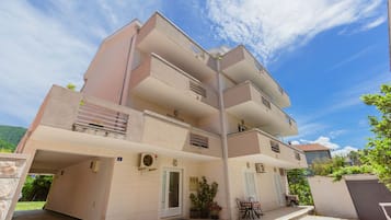 Un edificio residencial de varios pisos con balcones, una entrada cubierta y una pequeña zona de estar al aire libre.