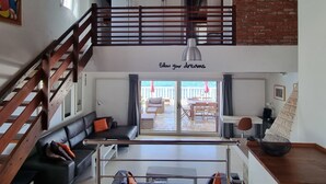 Un appartement-loft spacieux avec une mezzanine, un escalier, un balcon et une vue sur la terrasse extérieure.