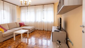 Een moderne woonkamer met een bank, salontafel en een televisie op een houten kast.