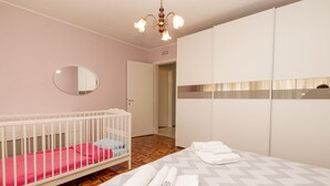 Een slaapkamer met een ledikant, een bed met opgerolde handdoeken, een spiegel en een kledingkast.