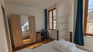 A bedroom with a bed, a wardrobe, a desk, and a window. - Appartement en Entier 2 Chambres 6 Couchages (Nancy)
