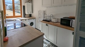 A compact kitchen with a washing machine, a microwave, and a toaster. - Appartement en Entier 2 Chambres 6 Couchages (Nancy)