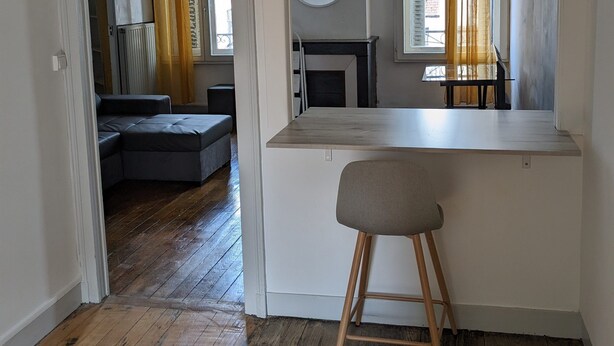 A compact living space with a kitchenette, a dining area, and a seating area with a sofa and a chair. - Appartement en Entier 2 Chambres 6 Couchages (Nancy)