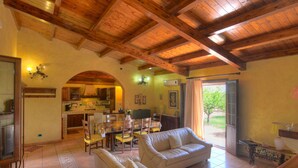 A spacious living area with a wooden ceiling, a dining table with chairs, a sofa, and a kitchen in the background. - Beautiful private villa with private pool, A/C, WIFI, TV, patio, pets allowed and panoramic view (Solarino)