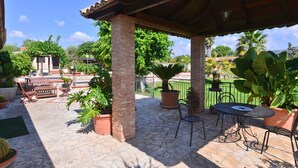 A covered patio area with stone flooring, outdoor furniture, and potted plants. - Beautiful private villa with private pool, A/C, WIFI, TV, patio, pets allowed and panoramic view (Solarino)