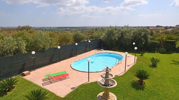 Ein Garten mit Swimmingpool, überdachter Sitzgelegenheit und einer Zierbrunnen.