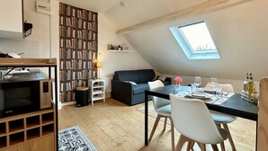Une pièce de style loft comprenant une table à manger, des chaises, un canapé, une bibliothèque et une lucarne.