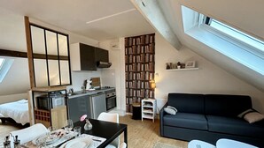 Une pièce de style loft comprenant un coin repas, une kitchenette et un canapé de couleur sombre.
