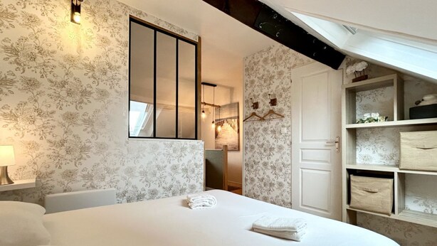 Une chambre d’hôtel avec un grand lit, une armoire, un miroir et un luminaire suspendu.