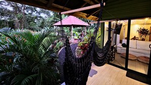 A cozy room with a hammock, a wooden ceiling, and a view of a lush garden. - Cabañas Caeli, Peaceful Rainforest Retreat with Stunning Views (Peñas Blancas)