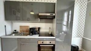 A modern kitchen with stainless steel appliances, a built-in oven, and a compact sink.