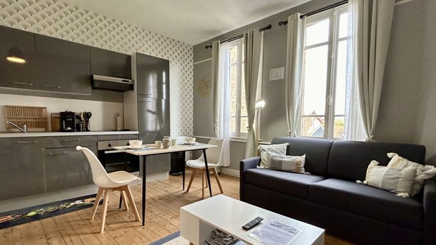 A modern living space with a kitchen, dining area, and a sofa.