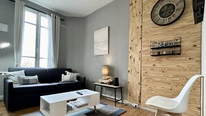 A modern living room with a black sofa, white coffee table, and a white chair.