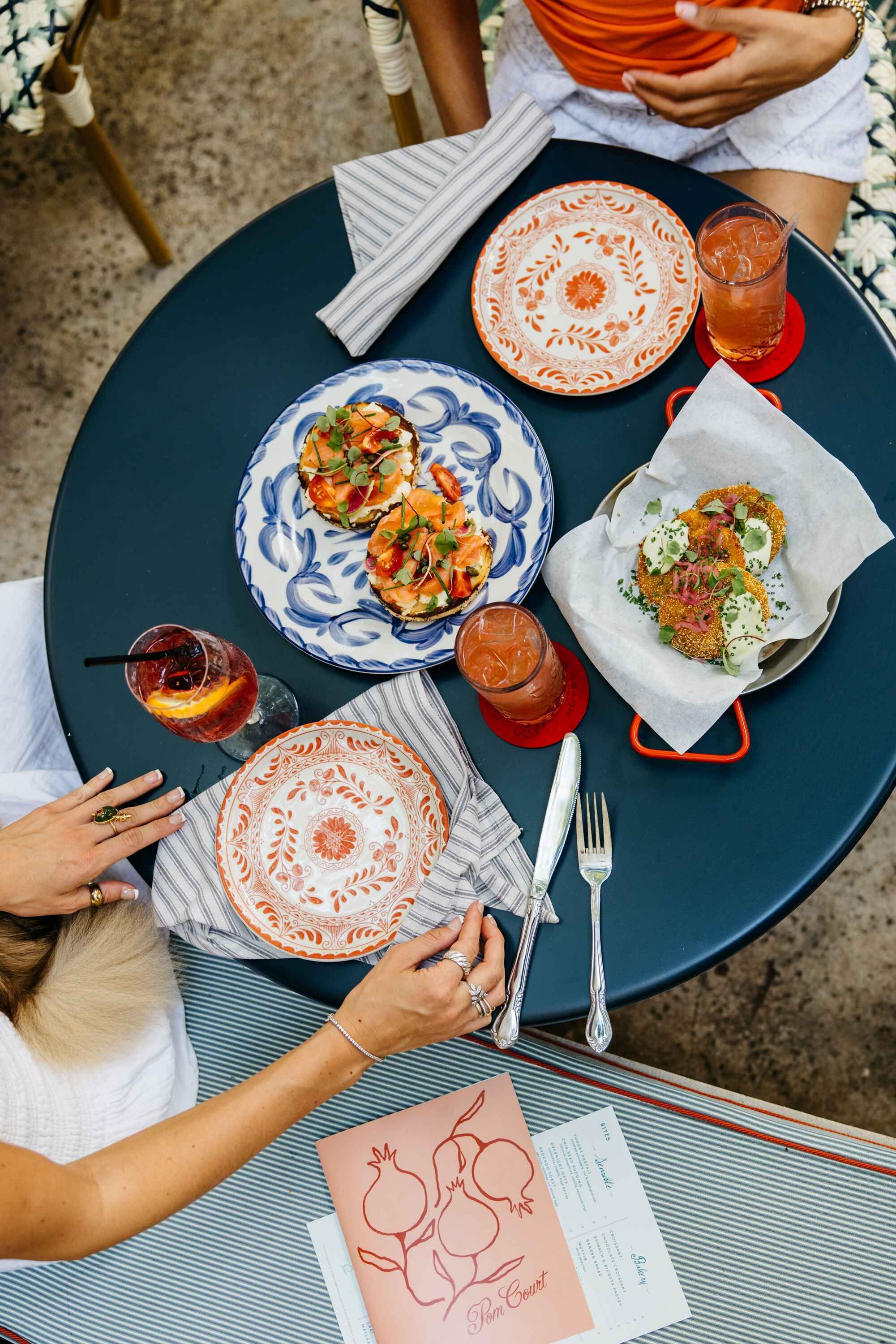 A round table with plates of food, drinks, and a menu.