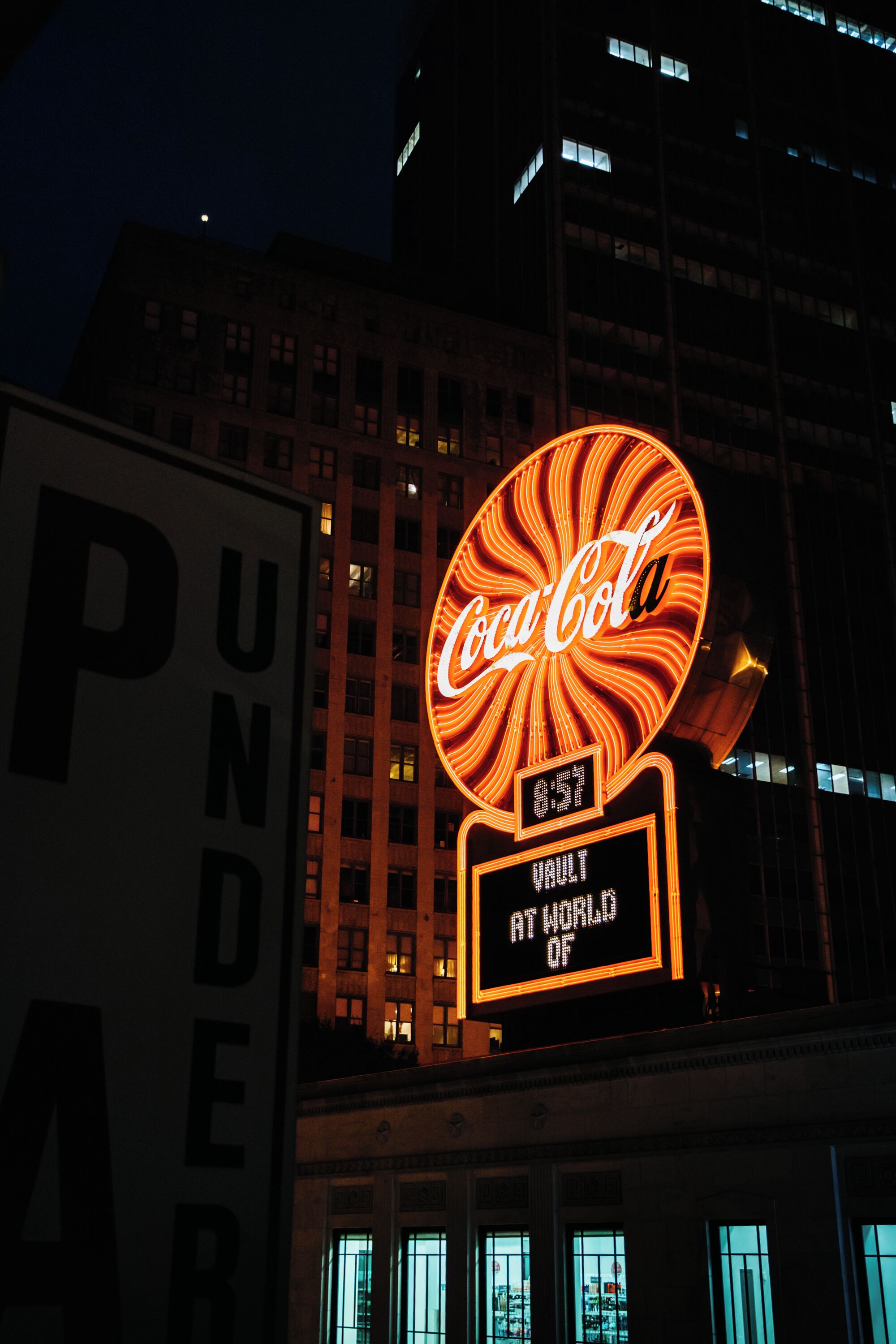 A building with a large Coca-Cola sign and a digital display reading "Vault at World of".