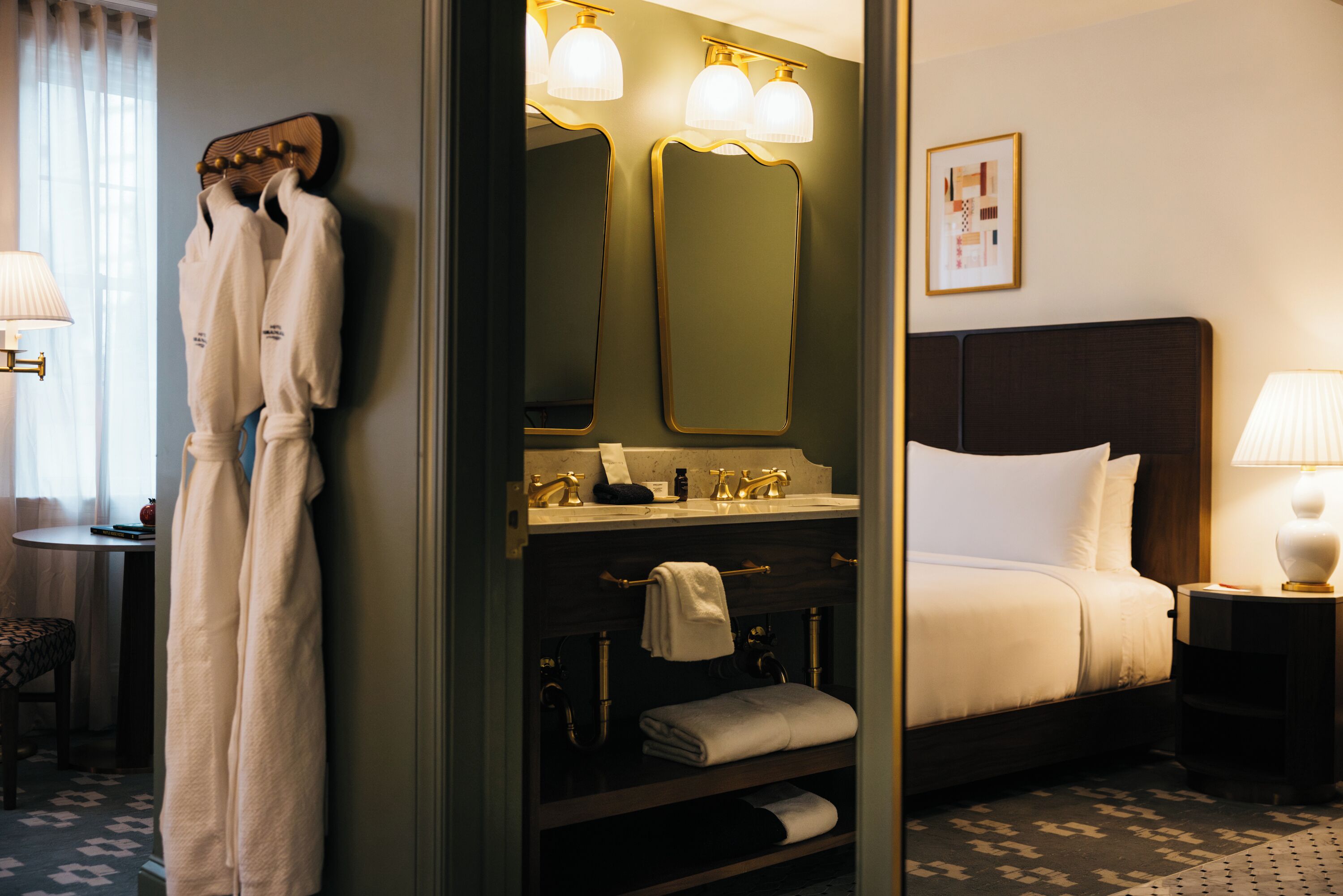 Quarto de hotel com cama, banheiro com espelho e porta-toalhas.