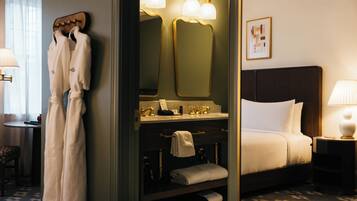 Quarto de hotel com cama, banheiro com espelho e porta-toalhas.