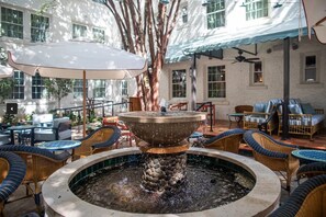 A courtyard with a central fountain, wicker furniture, and a building with large windows in the background. - Hotel Granada, a Member of Design Hotels (Atlanta)