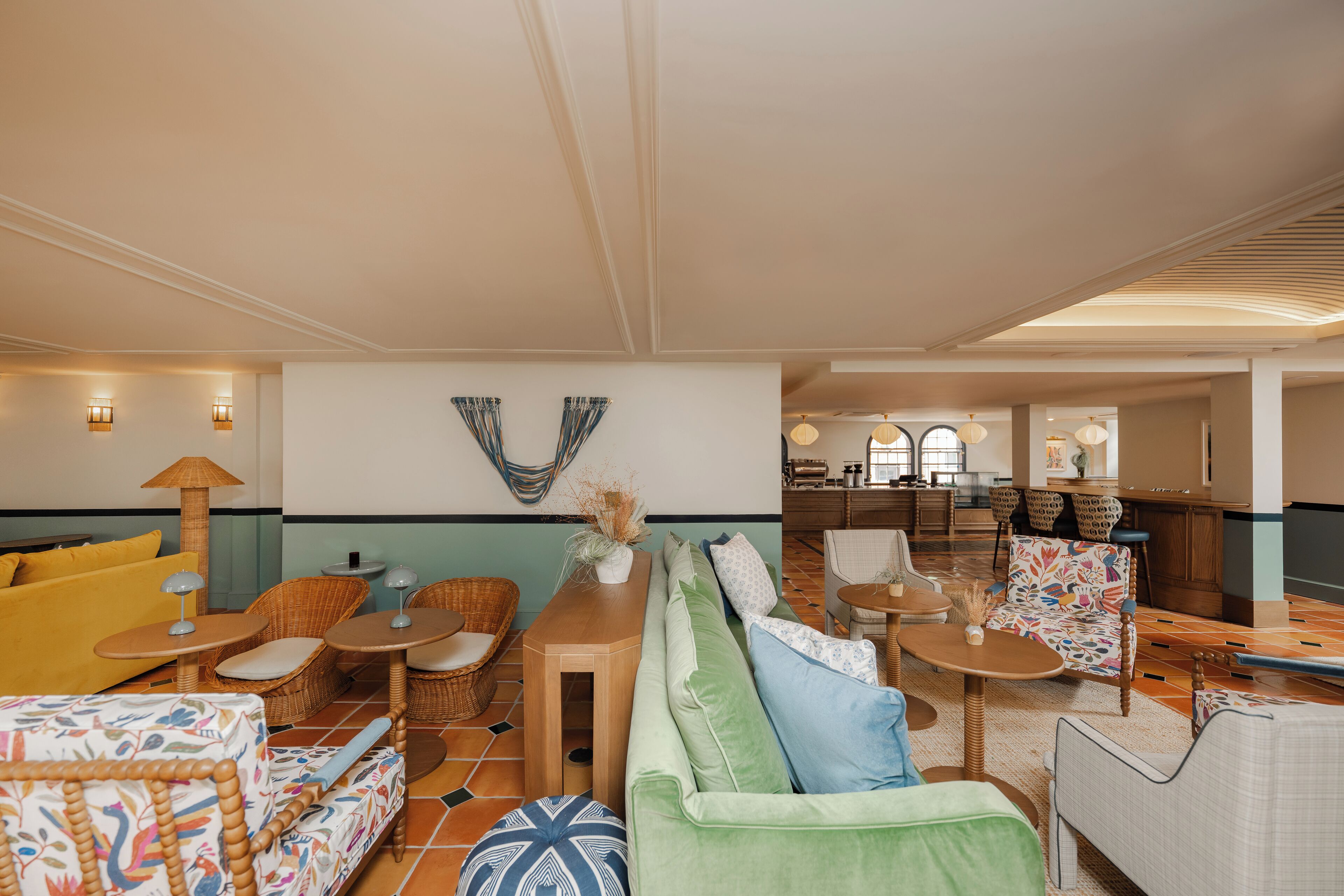 A spacious living area with a sofa, chairs, and a dining table. There is a kitchen area in the background.
