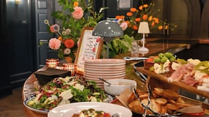 A buffet table with various food items, a floral centerpiece, and a sign indicating the menu. - Hotel Granada, a Member of Design Hotels (Atlanta)