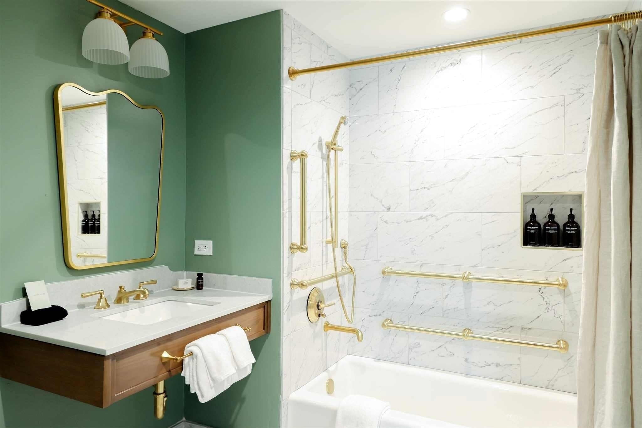 A bathroom with a vanity, two sinks, a bathtub, and a shower with gold fixtures.