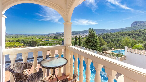 A balcony with a glass table and wicker chairs, overlooking a pool and a scenic landscape with mountains and greenery. - Gorgeous home in Orba (Orba)