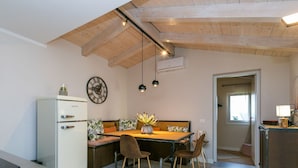 Une cuisine compacte dotée d’un réfrigérateur intégré, d’une table à manger en bois avec des chaises et d’un luminaire suspendu.