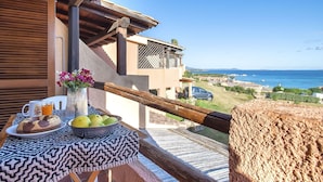 A balcony with a table set for breakfast, overlooking a coastal view. - Nice apartment for 4 guests with pool, A/C, TV, patio and pets allowed (Olbia)