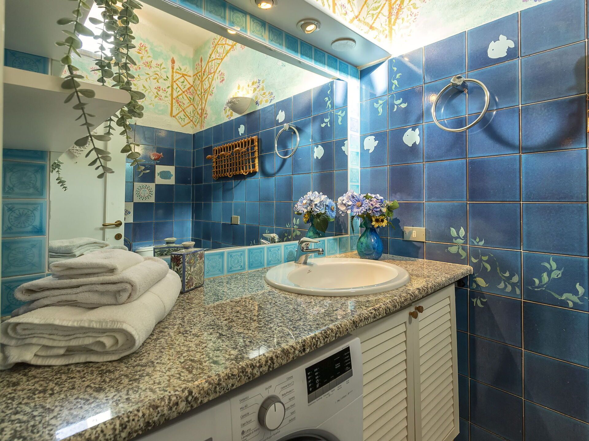 Een badkamer met een wastafel, spiegel en handdoeken.