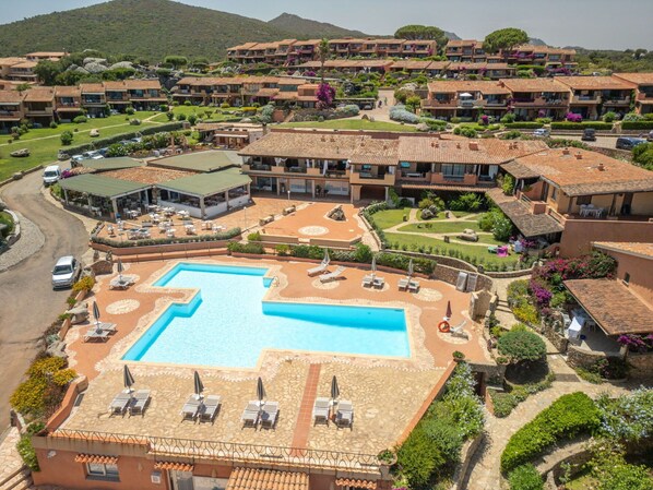Een resort met een centraal gelegen zwembad, meerdere gebouwen en aangelegde tuinen.