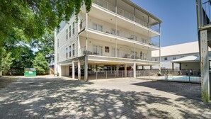 Un edificio a più piani con balconi, una zona esterna coperta e una piscina.
