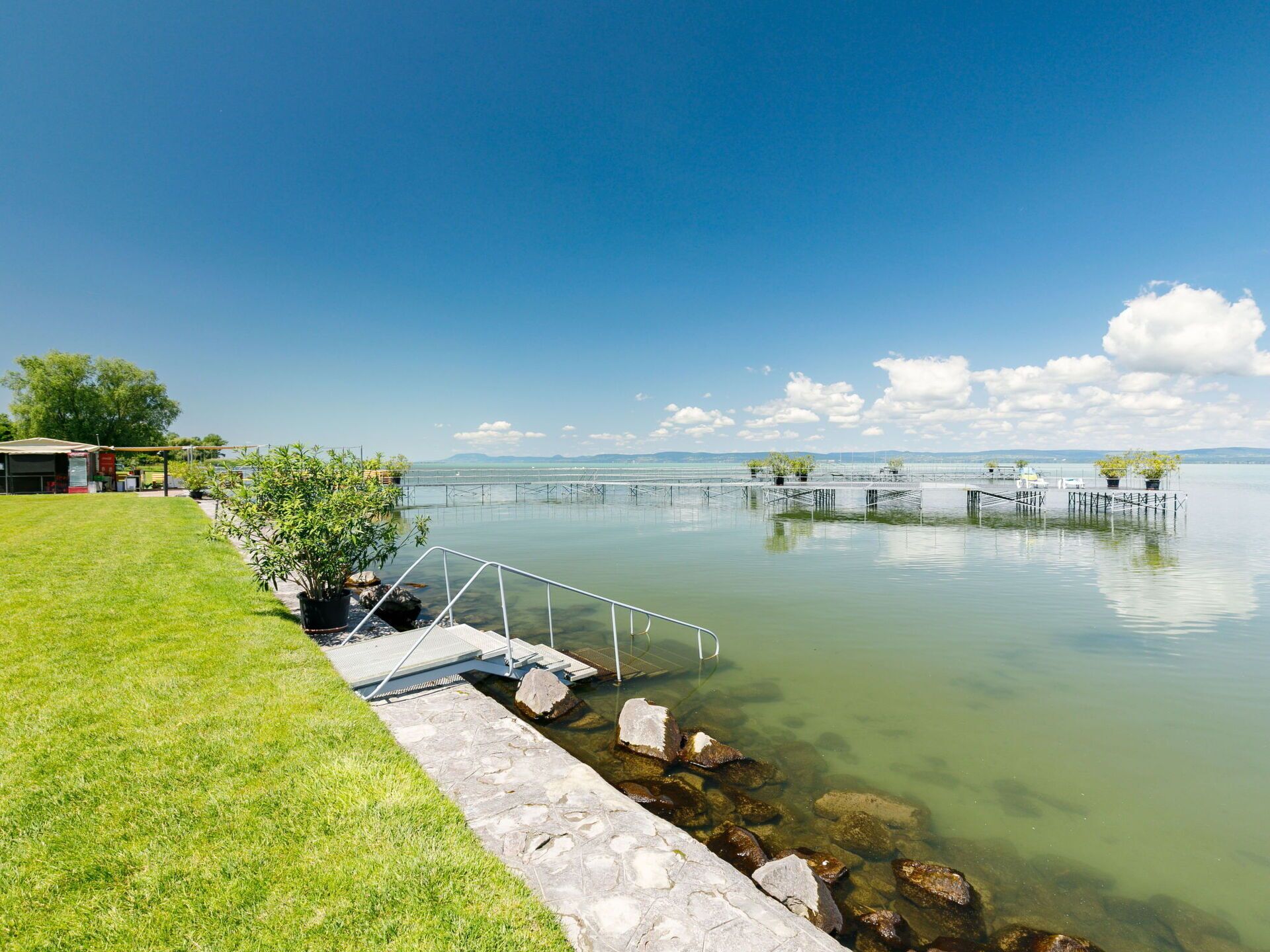 A lakeside property with a grassy area, a dock, and a small building.