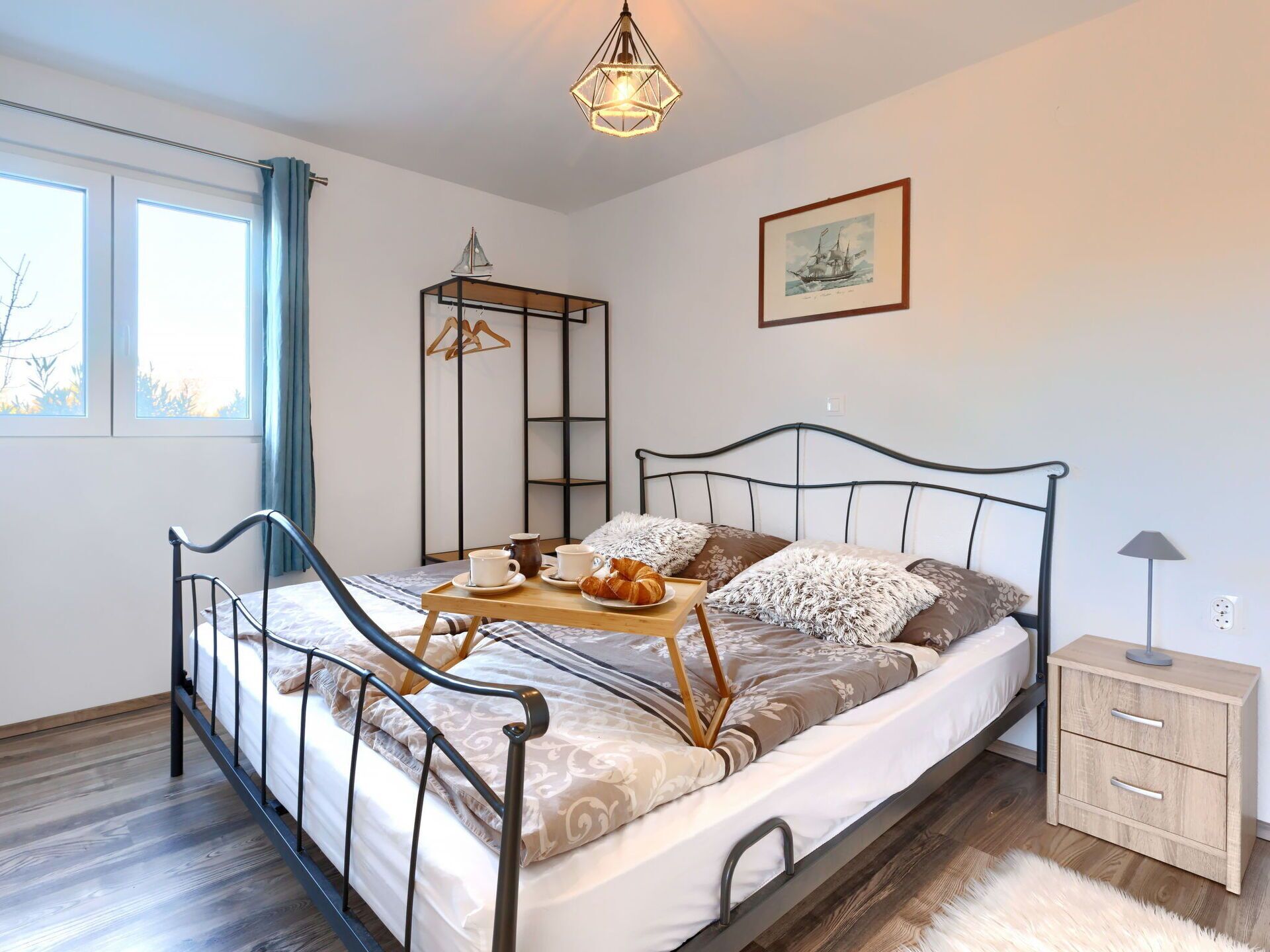 A bedroom with a bed, bedside table, and a window.
