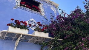 A building with a blue facade, a decorative window with red flowers, and a balcony with red flowers. - Stunning  villa for 6 guests with WIFI, A/C, TV and balcony (Partinico)