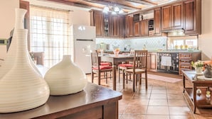 A kitchen with wooden cabinets, a dining area with chairs, a refrigerator, and a large vase on the counter. - Stunning  villa for 6 guests with WIFI, A/C, TV and balcony (Partinico)