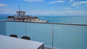 A balcony with a view of the sea and a building with a flagpole. - Cosy apartment for 6 guests with A/C, WIFI, TV, balcony and pets allowed (Lignano Sabbiadoro)