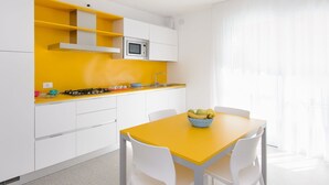 A modern kitchen with white cabinets, a yellow countertop, and a dining table with chairs. - Lovely apartment for 4 guests with A/C, WIFI, TV, balcony and pets allowed (Lignano Sabbiadoro)