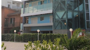A multi-story building with a glass facade and balconies. - Lovely apartment for 4 guests with A/C, WIFI, TV, balcony and pets allowed (Lignano Sabbiadoro)