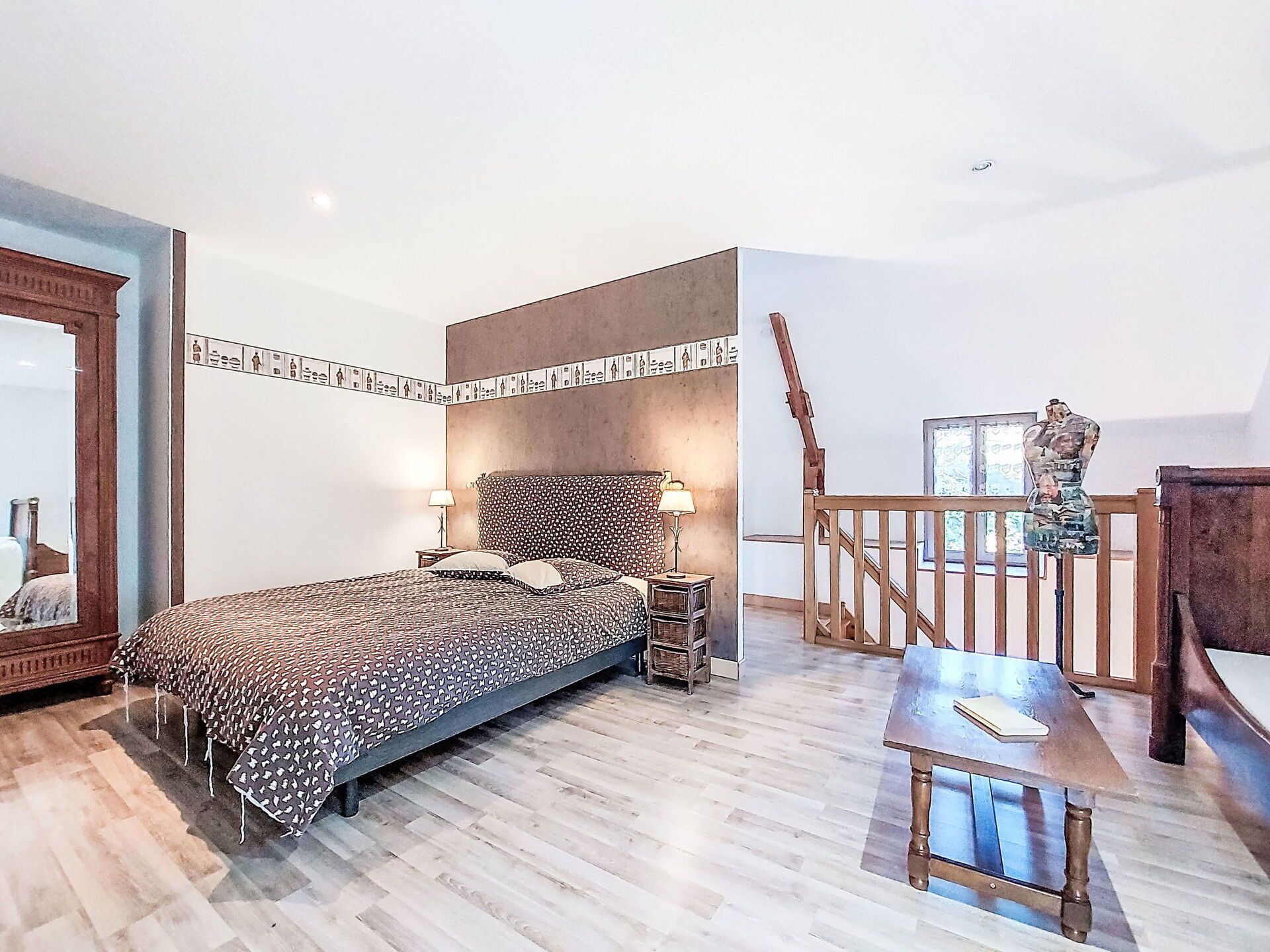 Un dormitorio con cama, mesitas de noche, cómoda, espejo y una escalera.