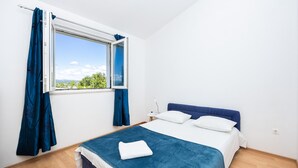 Une chambre à coucher avec un lit, une fenêtre avec des rideaux et une vue sur la verdure.